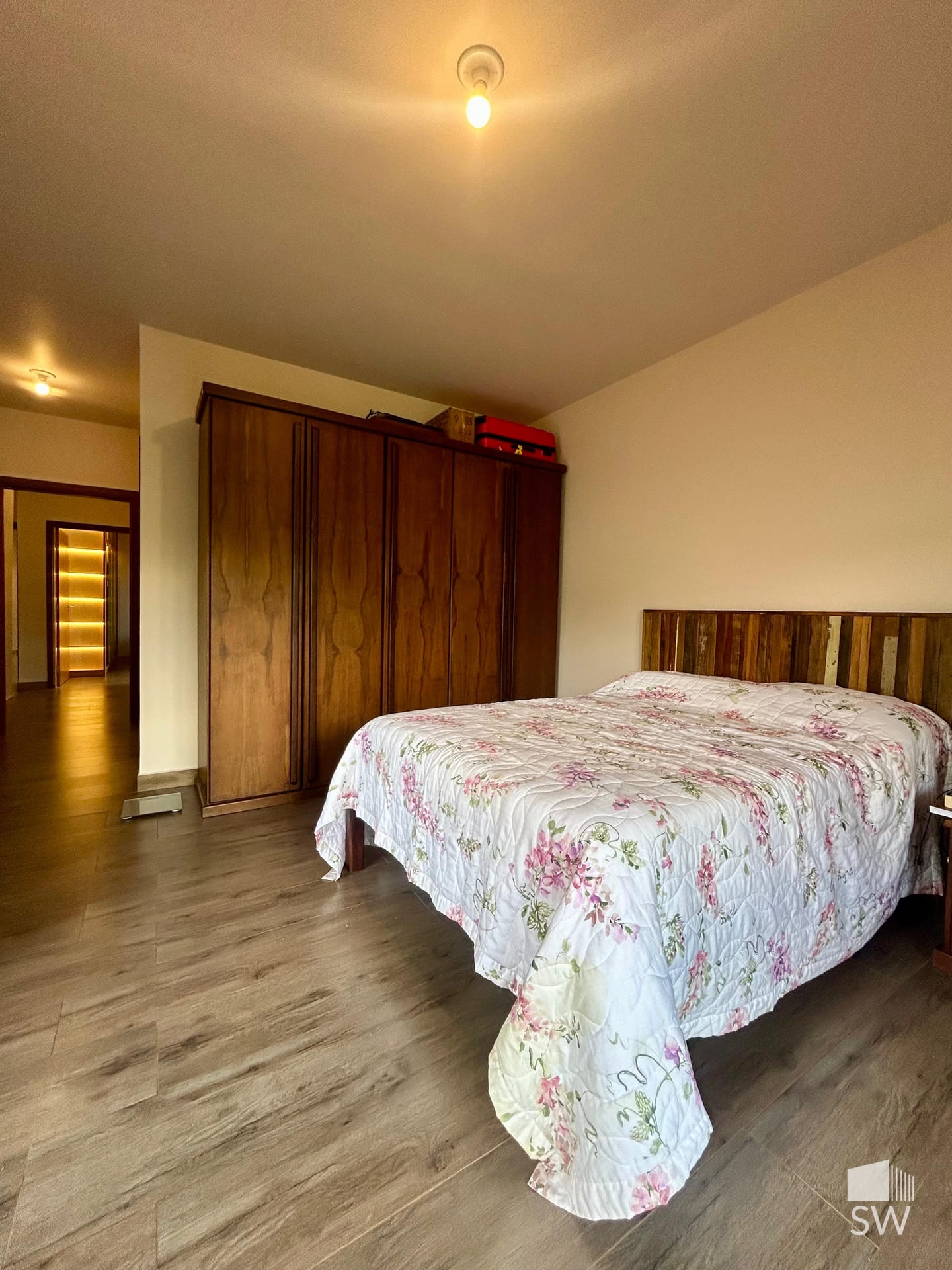 Suíte com cama de casal e guarda-roupa de madeira maciça