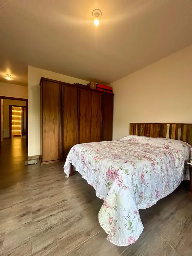Suíte com cama de casal e guarda-roupa de madeira maciça
